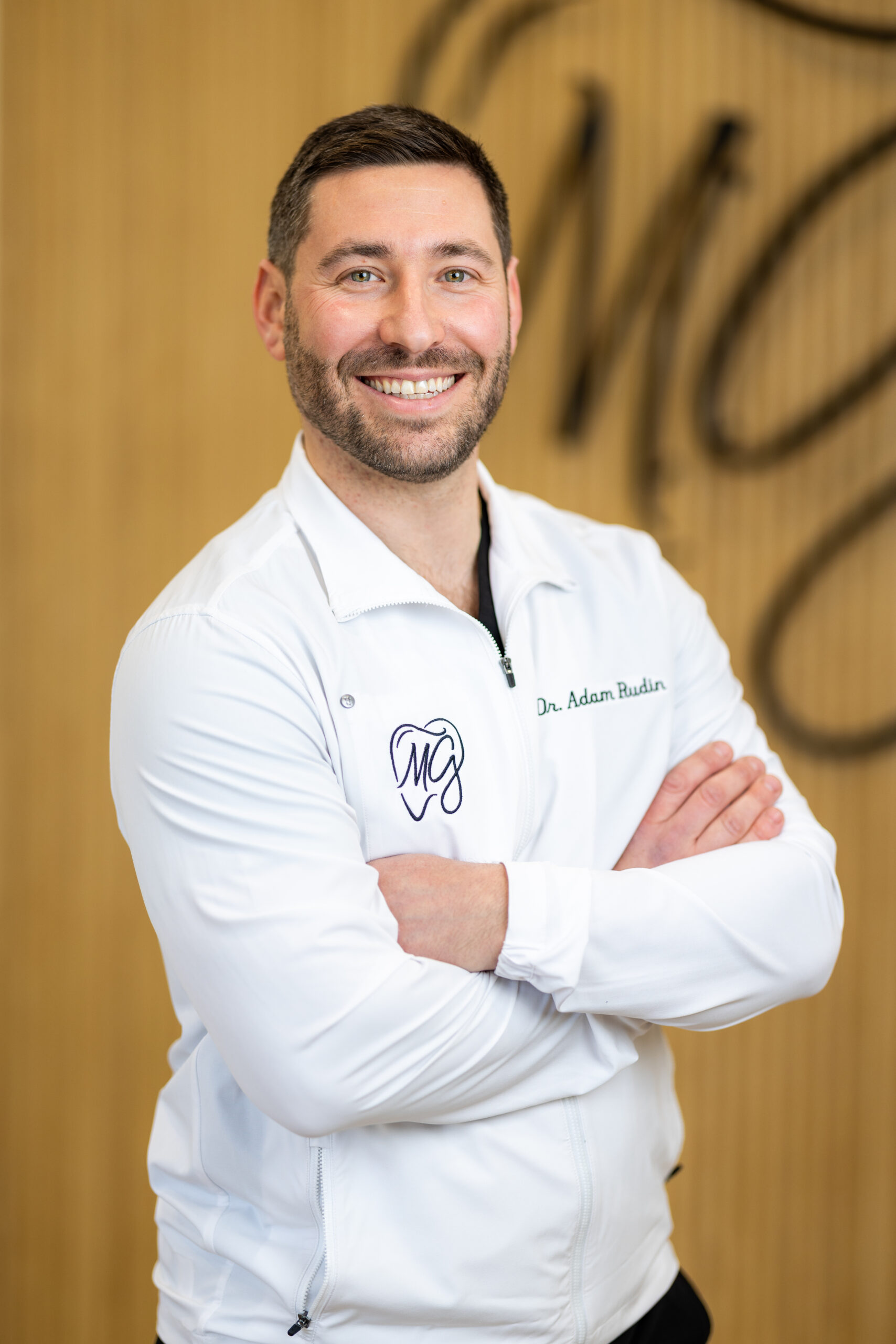 Dr. Adam Rudin and three smiling female dental team members standing together in front of the Maple Glen Modern Dentistry logo