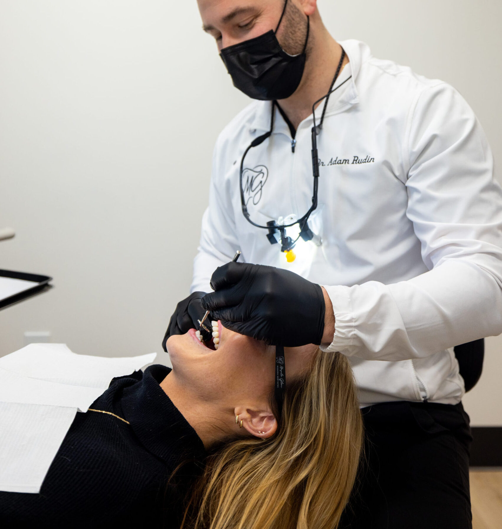 Dr. Adam Rudin wearing magnification loupes performing a dental exam on a female patient