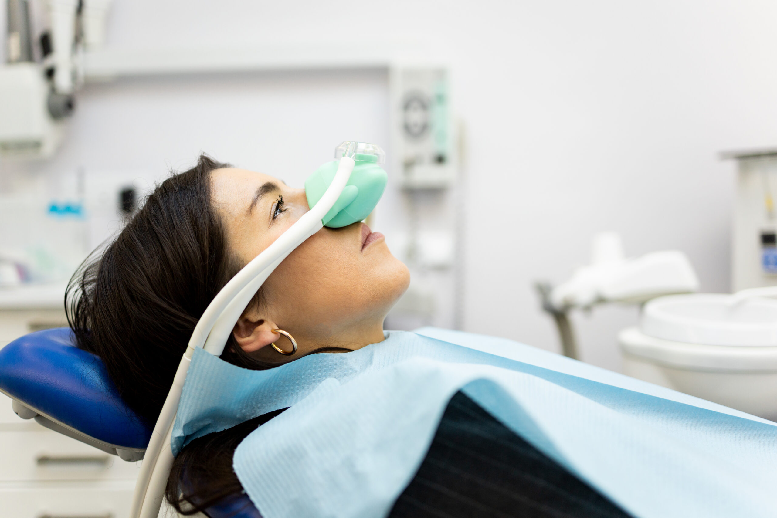 dental assistant placing a nitrous oxide nasal mask on a relaxed female patient