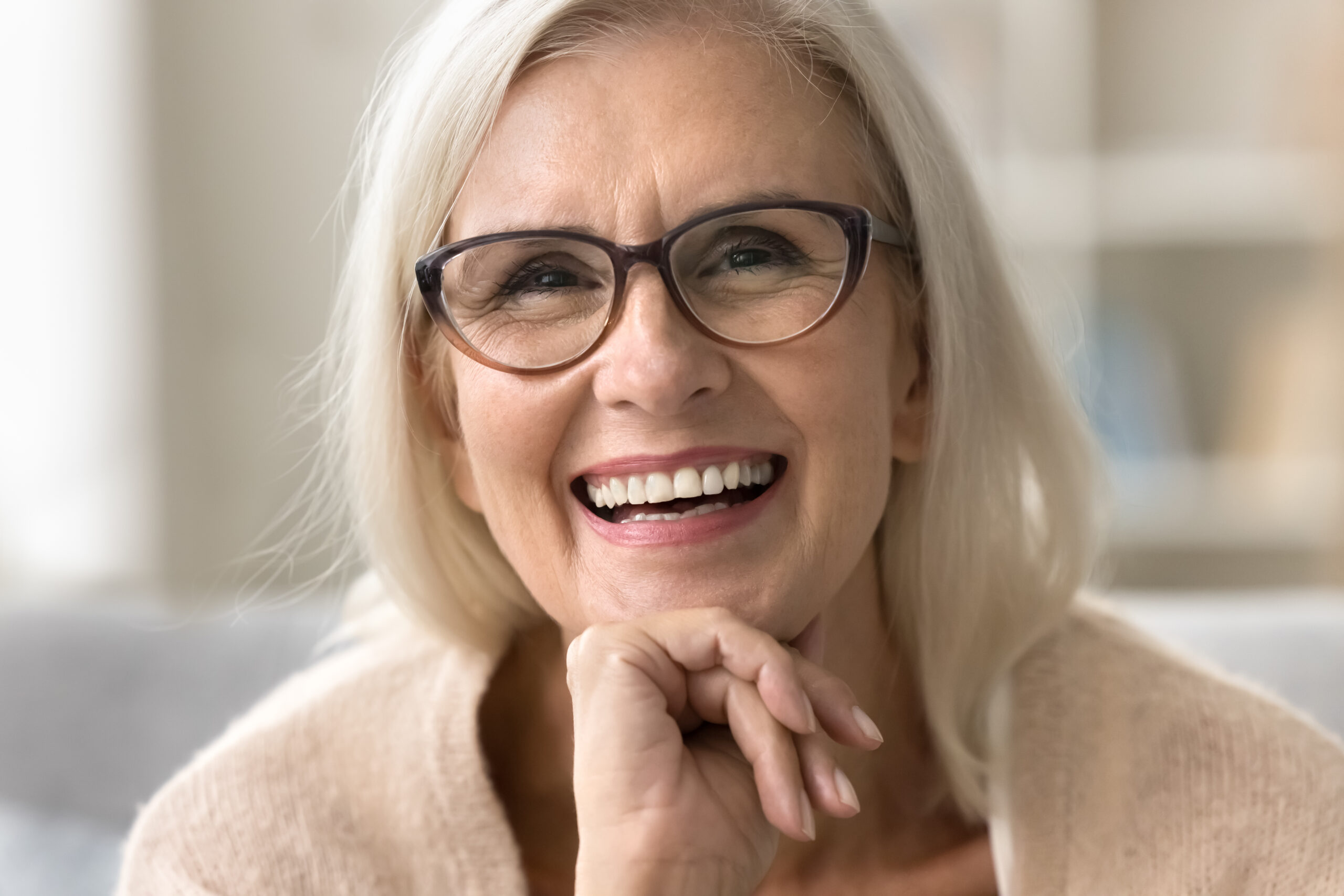 Older woman with glasses laughing and showing bright white teeth