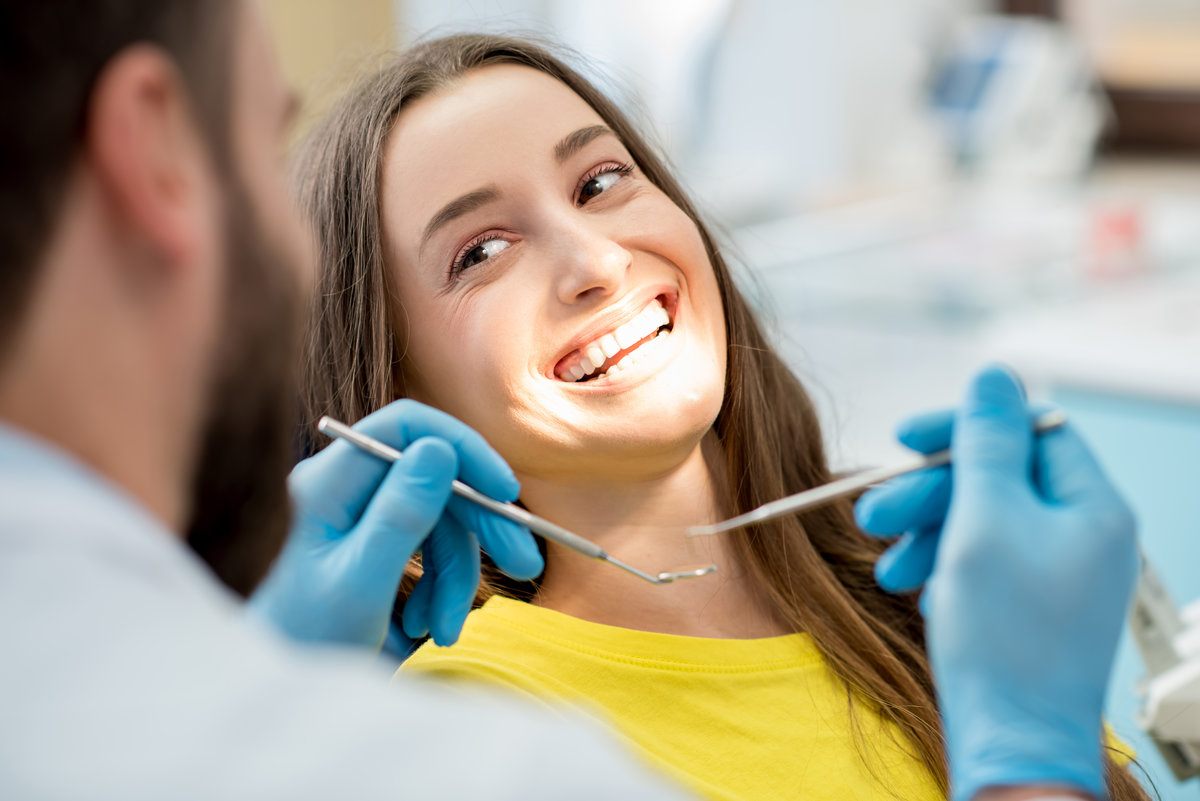 Portrait of a woman with toothy smile sitting during examination at the dental office