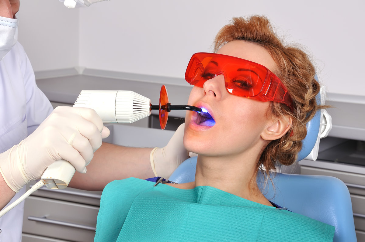 girl teeth stopping treatment with dental curing ultraviolet light equipment
