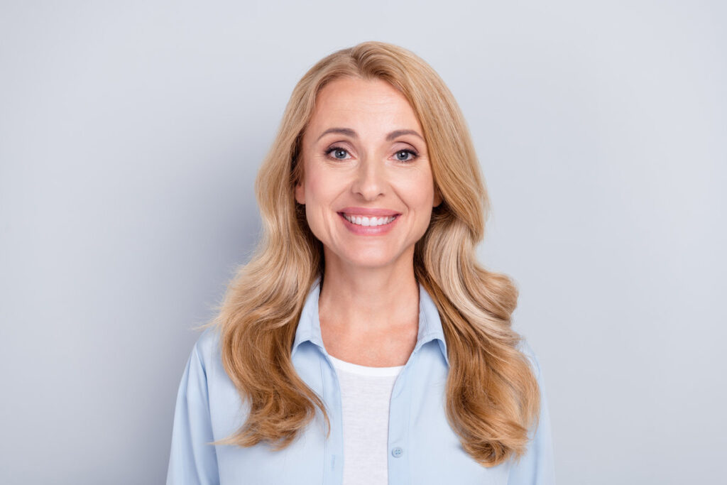 Photo of smiling cheerful mature woman smiling stomatology treatment new veneers isolated on grey color background.
